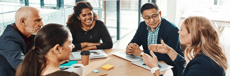 team of people sitting around a table in a mieeting